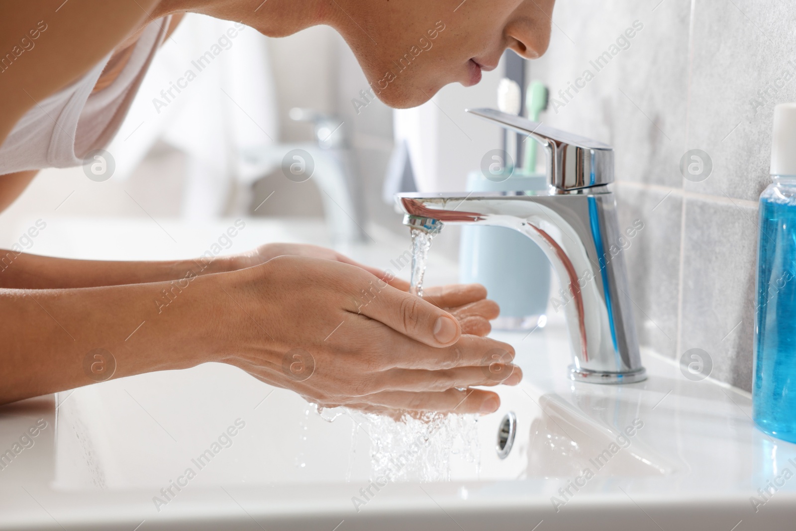 Photo of Man washing his face over sink in bathroom, closeup