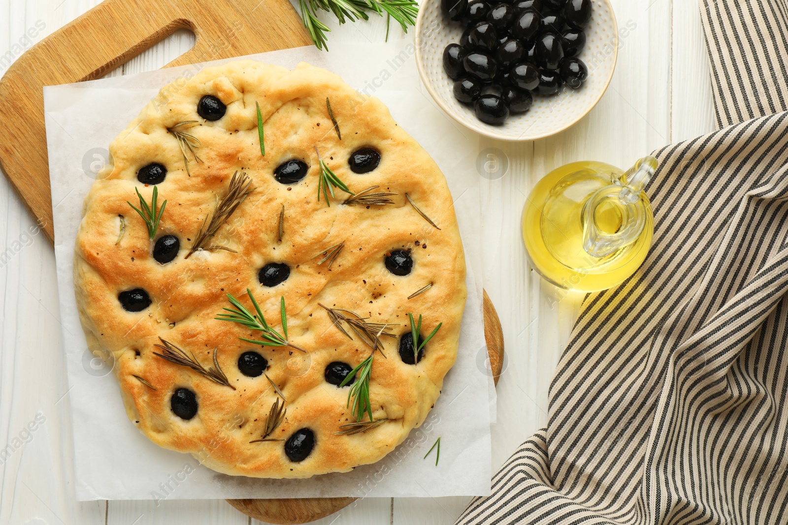 Delicious focaccia bread with olives, rosemary and oil on white wooden table, flat lay Photo of Delicious focaccia bread with olives, rosemary and oil on white wooden table, flat lay