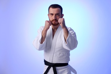 Photo of Karate fighter in uniform on violet background