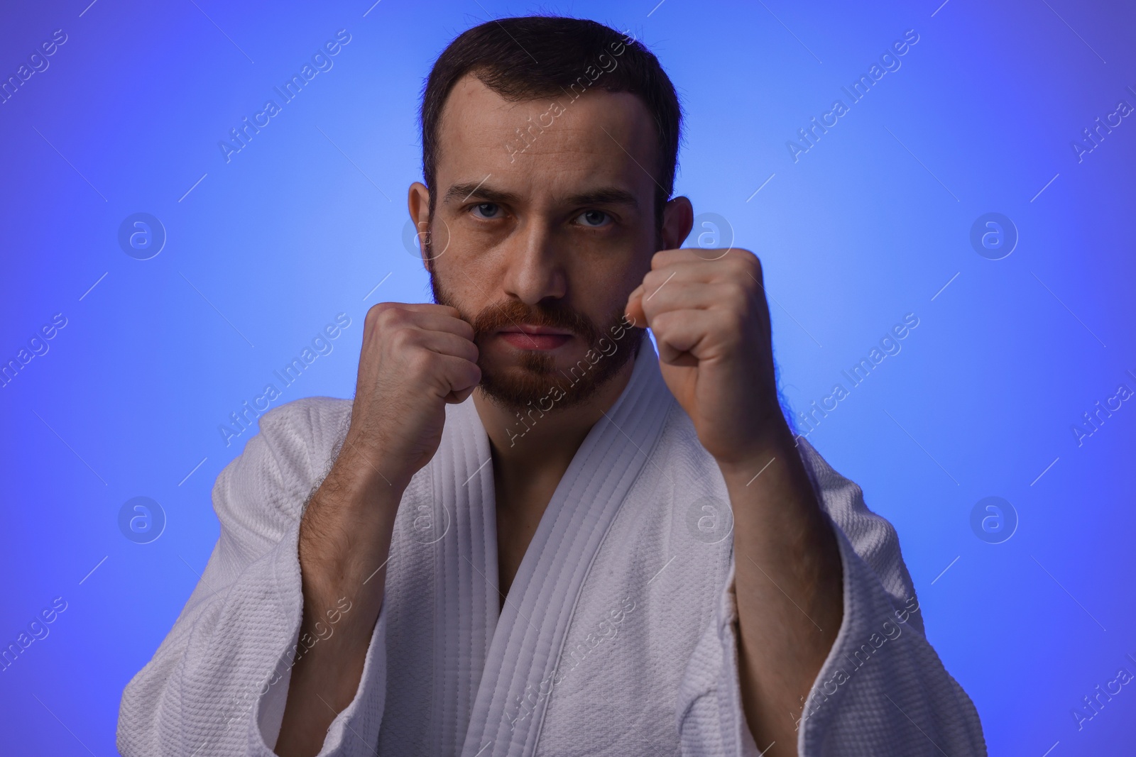 Photo of Karate fighter in uniform on blue background