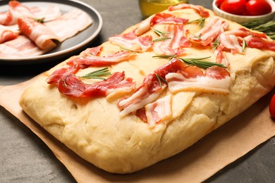 Photo of Delicious focaccia bread with bacon and rosemary on black table, closeup