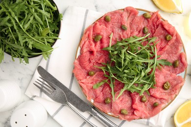 Photo of Delicious beef carpaccio served on white marble table, flat lay