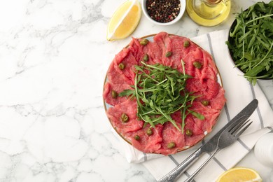 Delicious beef carpaccio served on white marble table, flat lay. Space for text