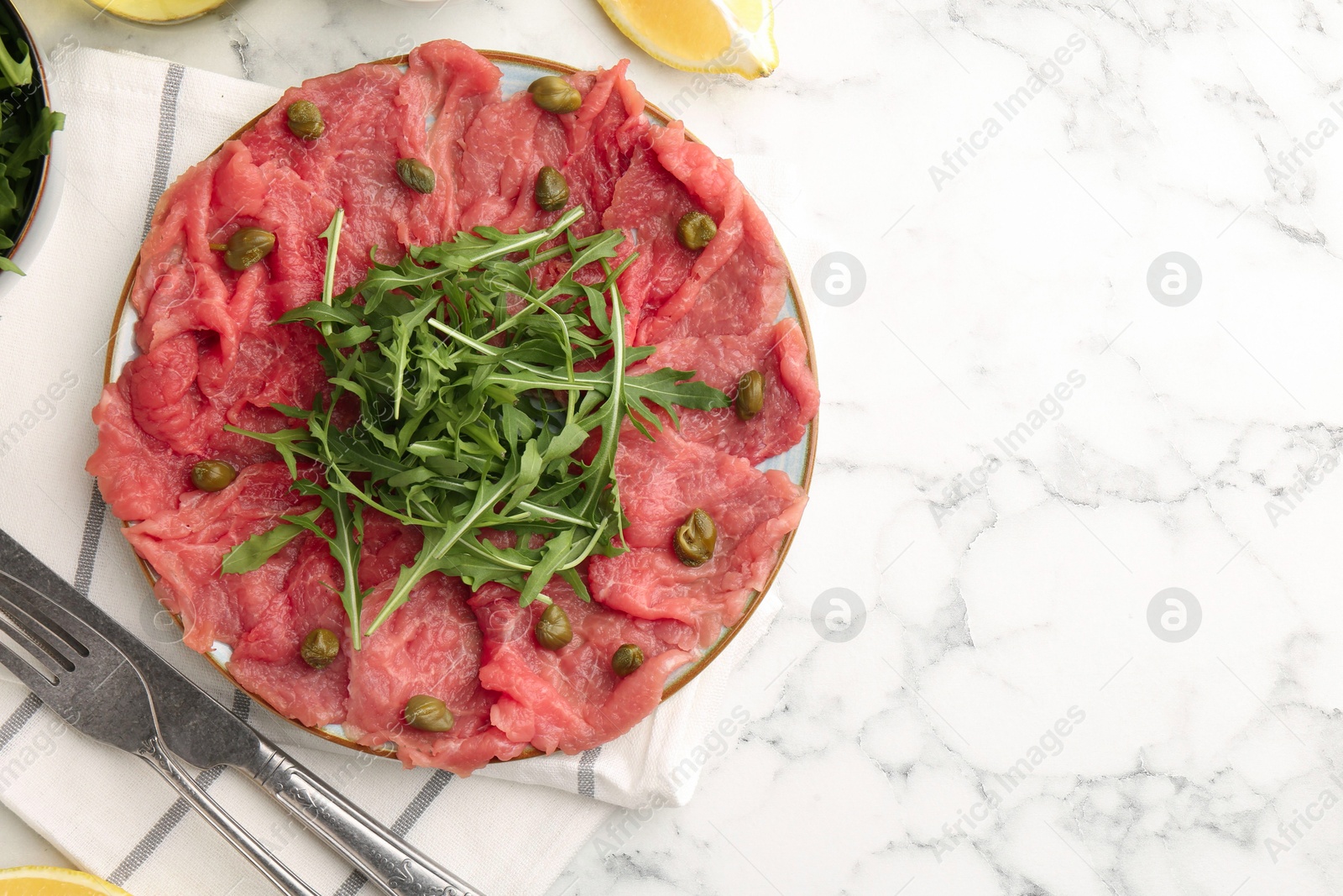 Photo of Delicious beef carpaccio served on white marble table, flat lay. Space for text