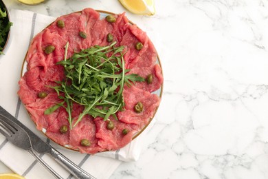 Delicious beef carpaccio served on white marble table, flat lay. Space for text