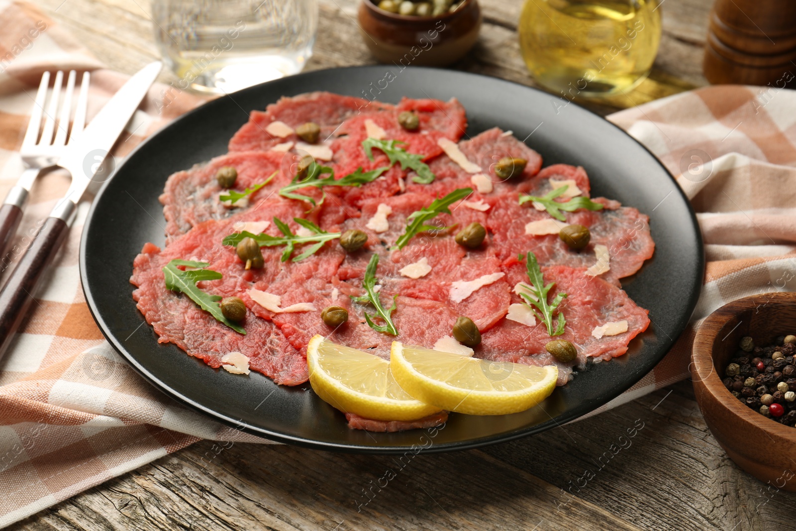 Photo of Delicious beef carpaccio served on wooden table, closeup