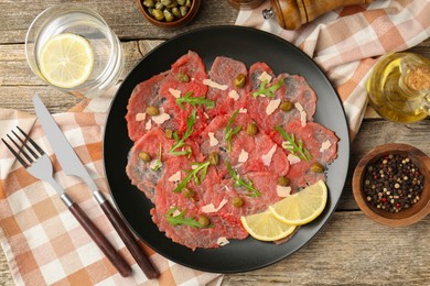 Photo of Delicious beef carpaccio served on wooden table, flat lay