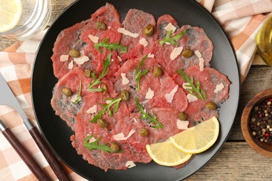 Delicious beef carpaccio served on wooden table, flat lay