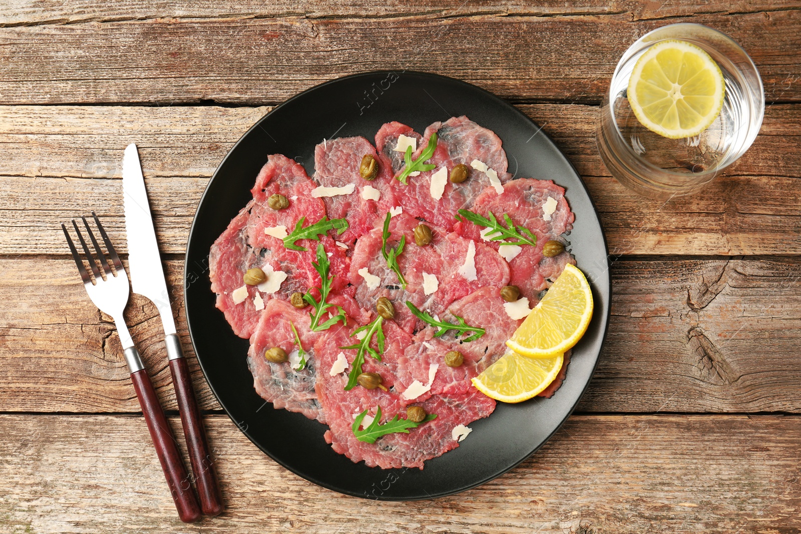 Photo of Delicious beef carpaccio served on wooden table, flat lay