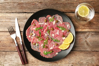 Photo of Delicious beef carpaccio served on wooden table, flat lay