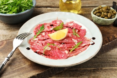 Photo of Delicious beef carpaccio served on wooden table, closeup