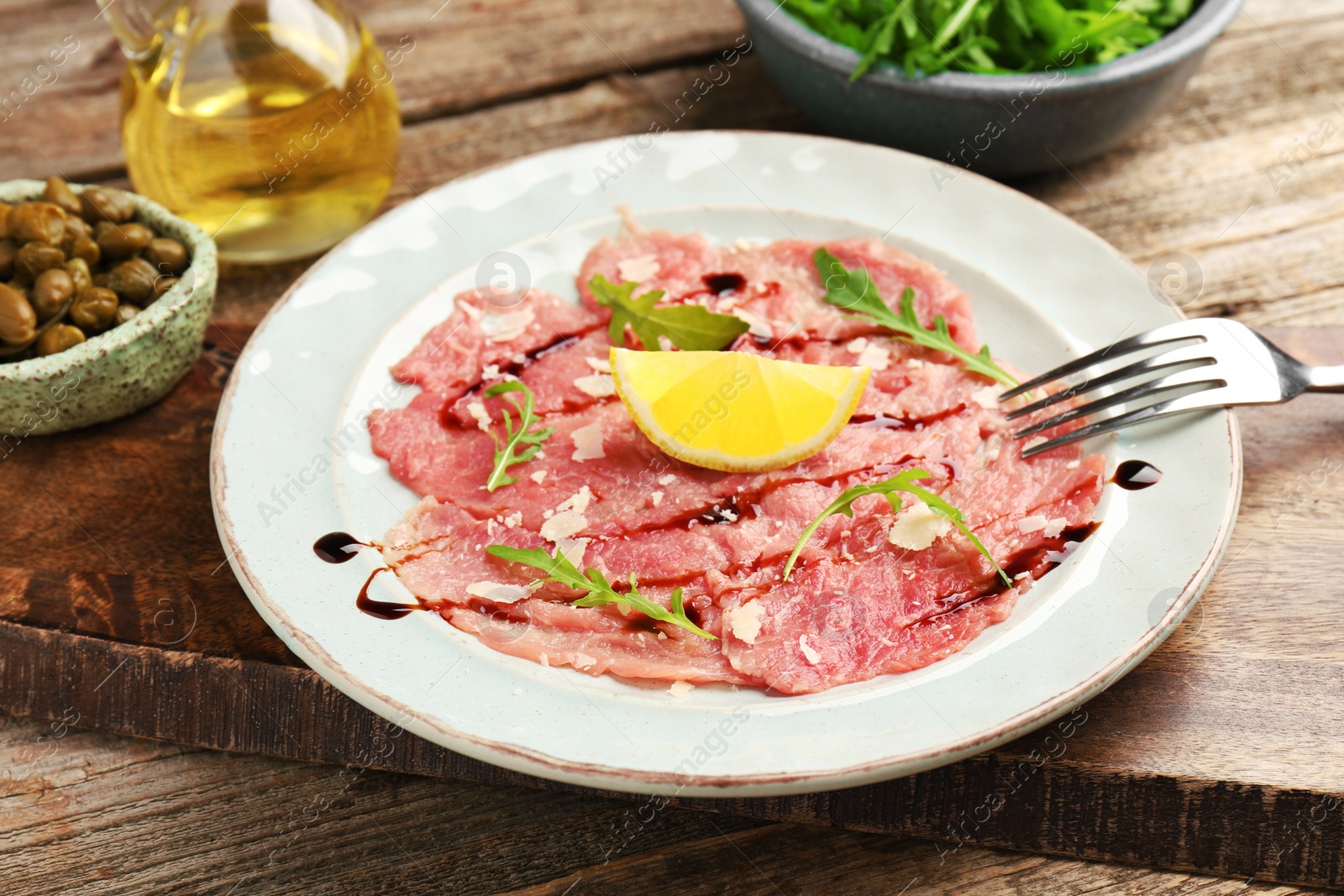 Photo of Delicious beef carpaccio served on wooden table, closeup