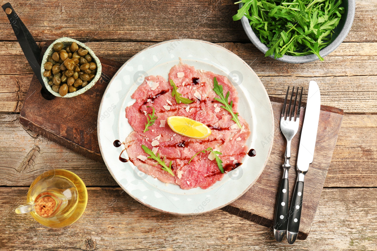 Photo of Delicious beef carpaccio served on wooden table, flat lay