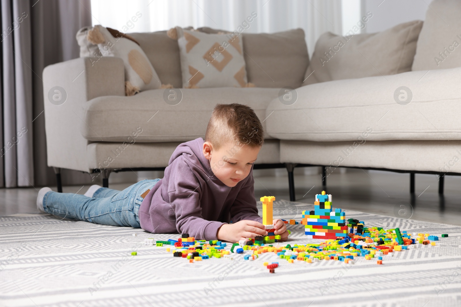 Photo of Cute boy playing with building blocks on floor at home