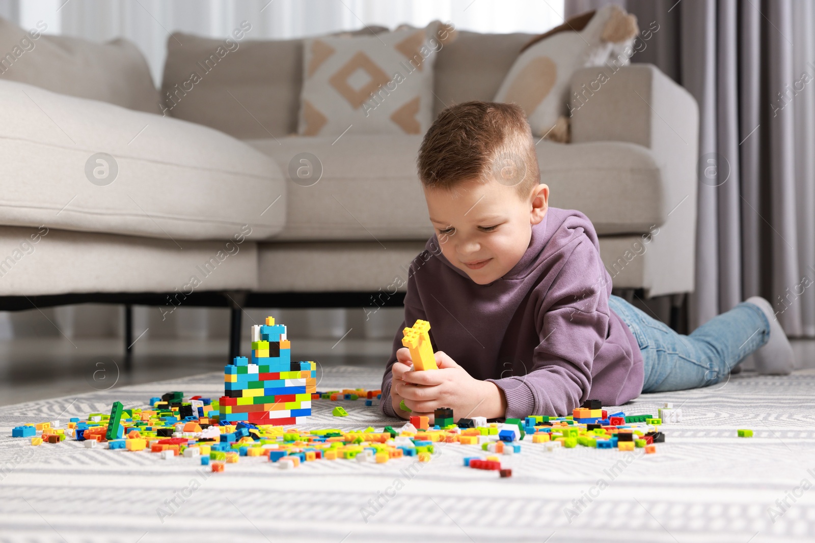 Photo of Cute boy playing with building blocks on floor at home. Space for text