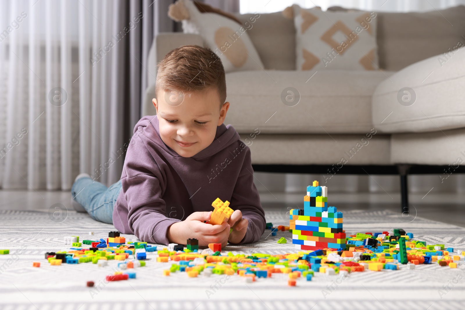 Photo of Cute boy playing with building blocks on floor at home. Space for text