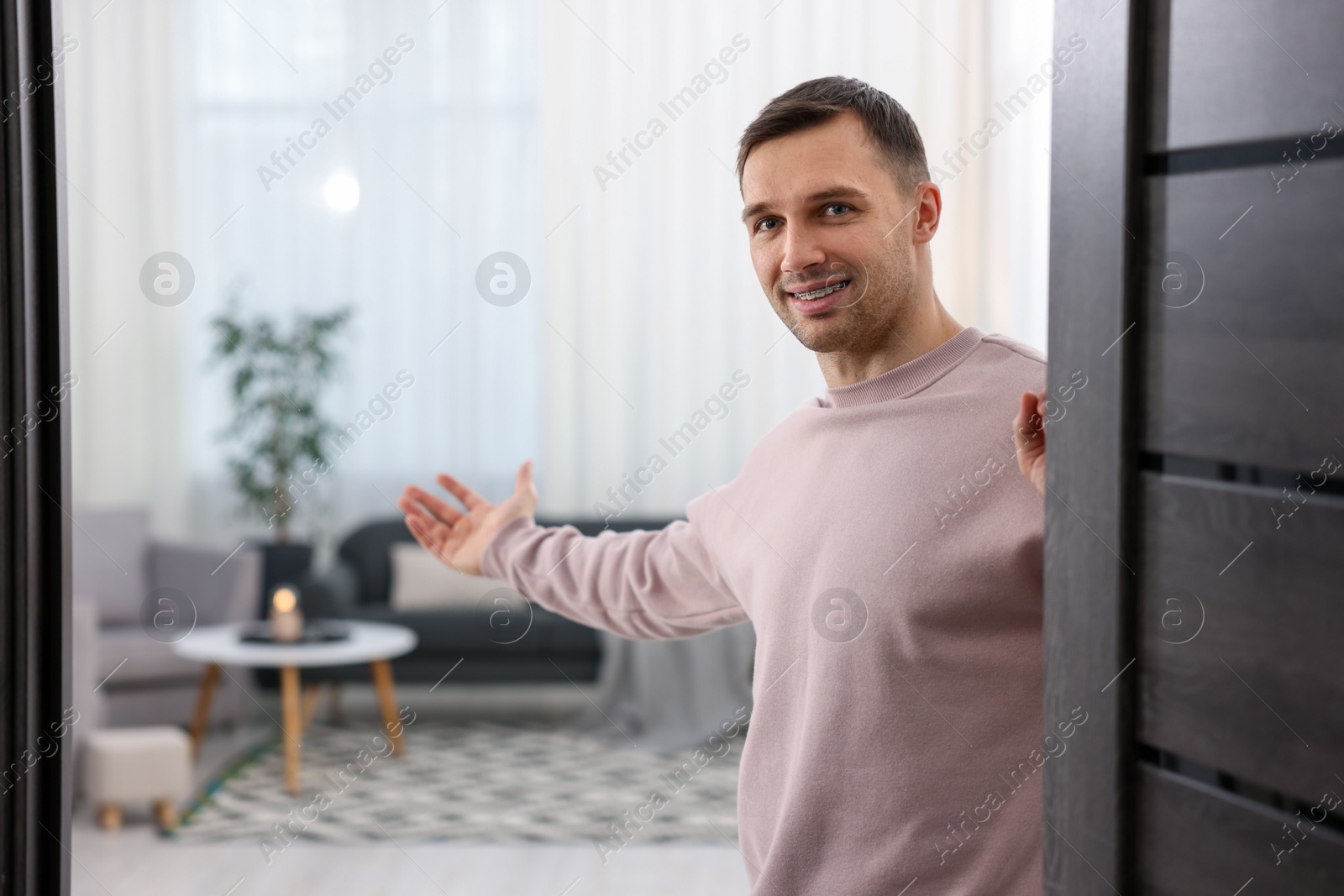 Photo of Cheerful man welcoming guests to his apartment