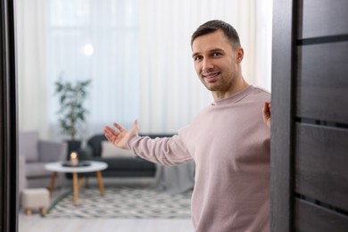 Photo of Cheerful man welcoming guests to his apartment