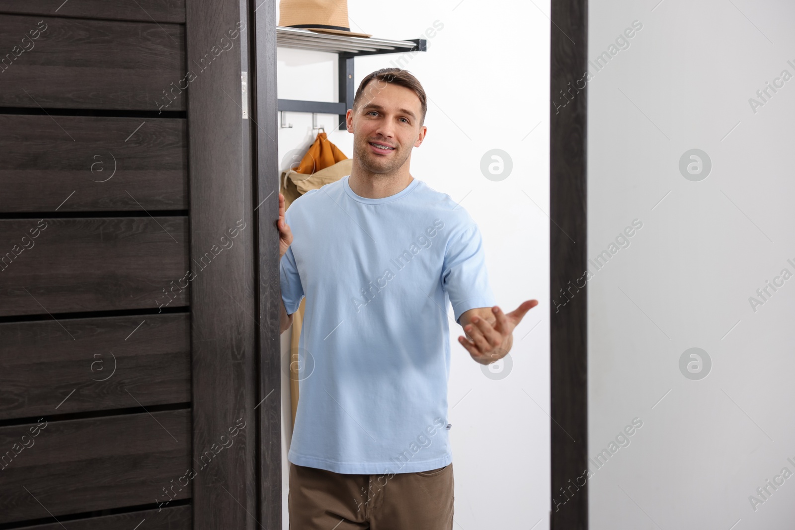 Photo of Cheerful man welcoming guests to his apartment