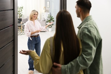 Photo of Happy woman welcoming friends to her apartment