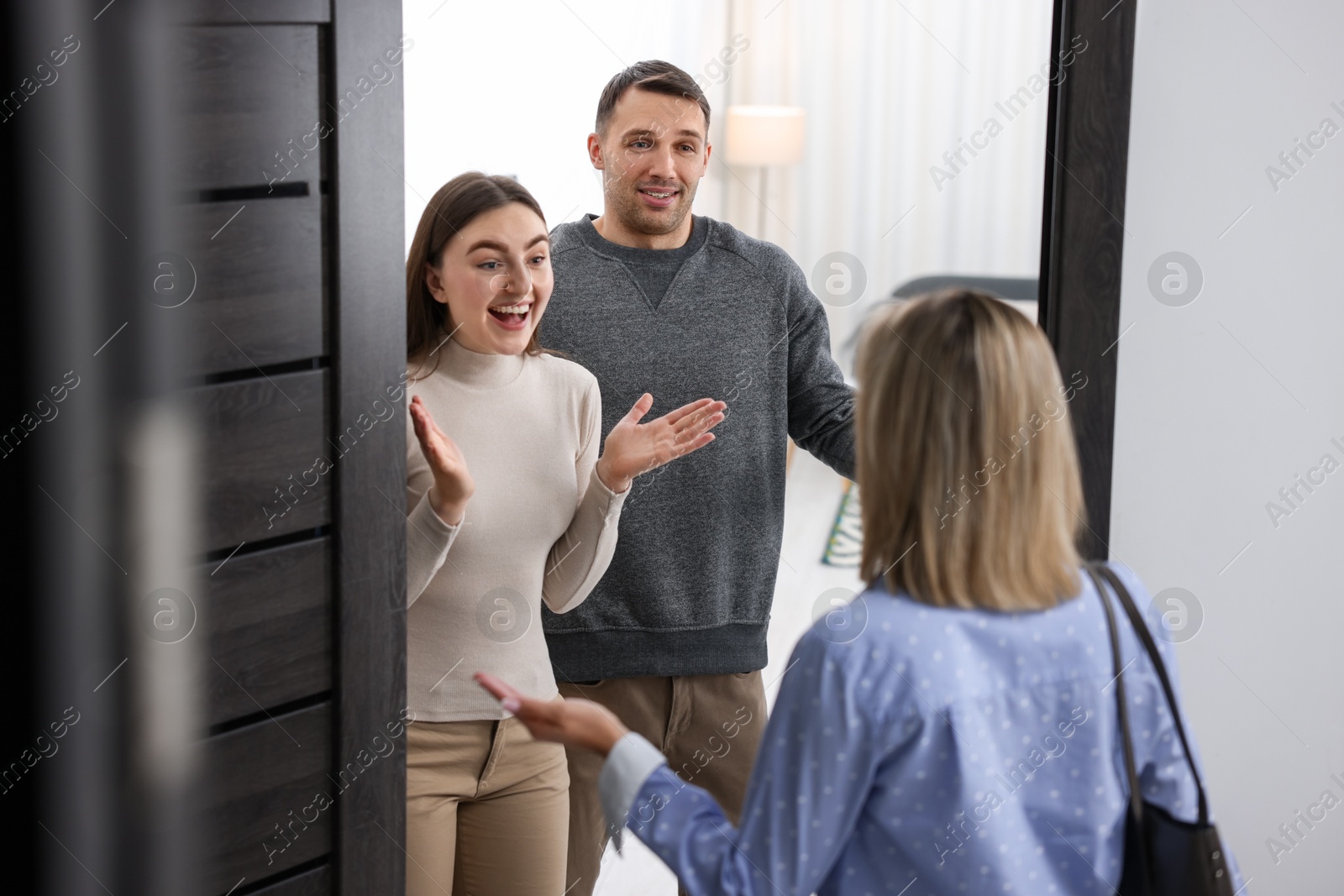 Photo of Lovely couple welcoming friend to their apartment