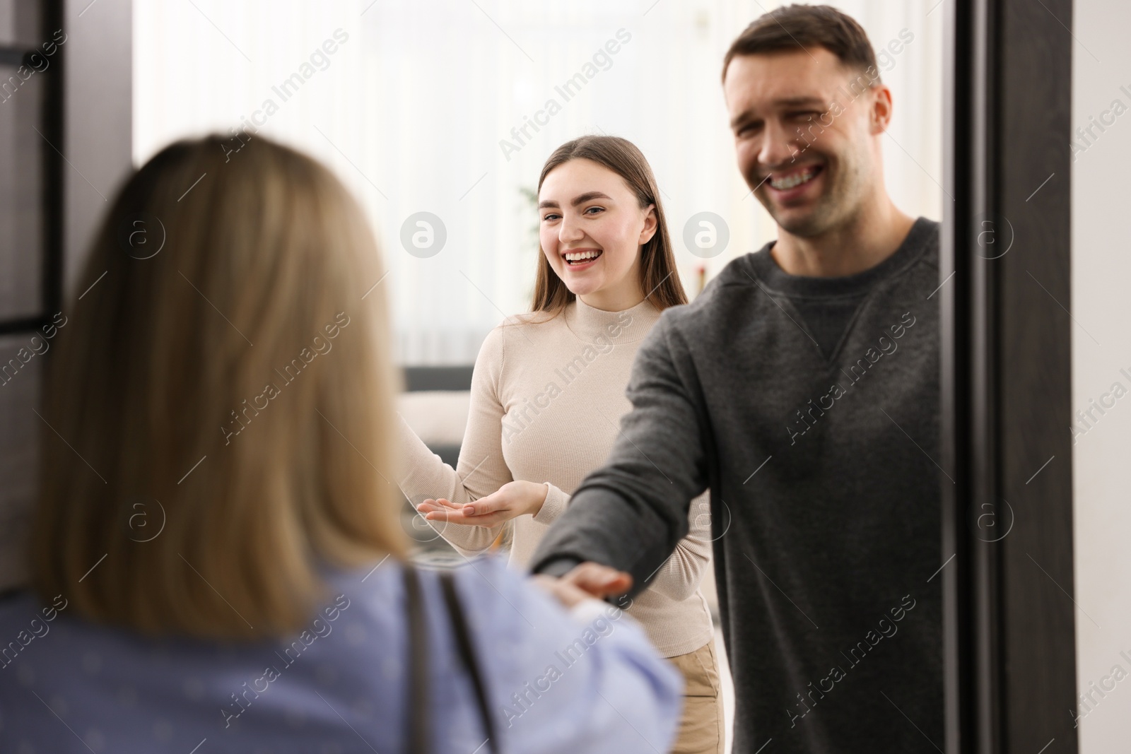 Photo of Lovely couple welcoming friend to their apartment