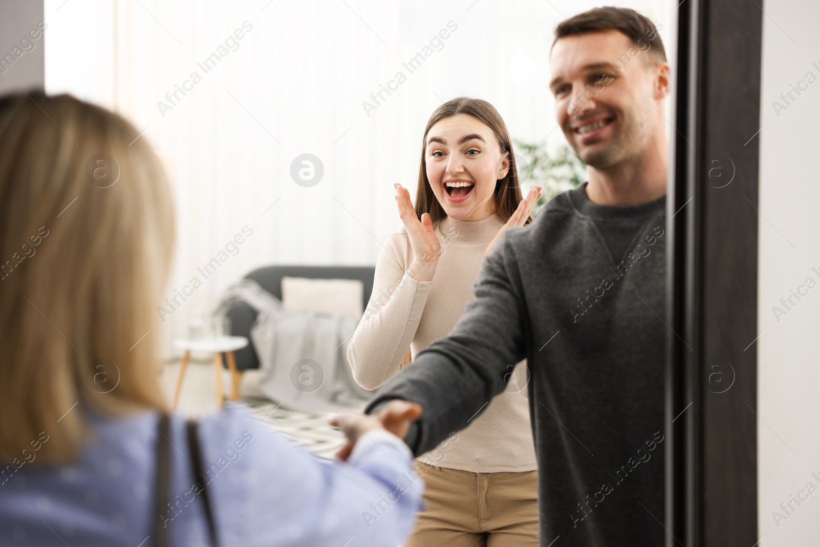 Photo of Lovely couple welcoming friend to their apartment