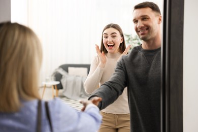 Photo of Lovely couple welcoming friend to their apartment