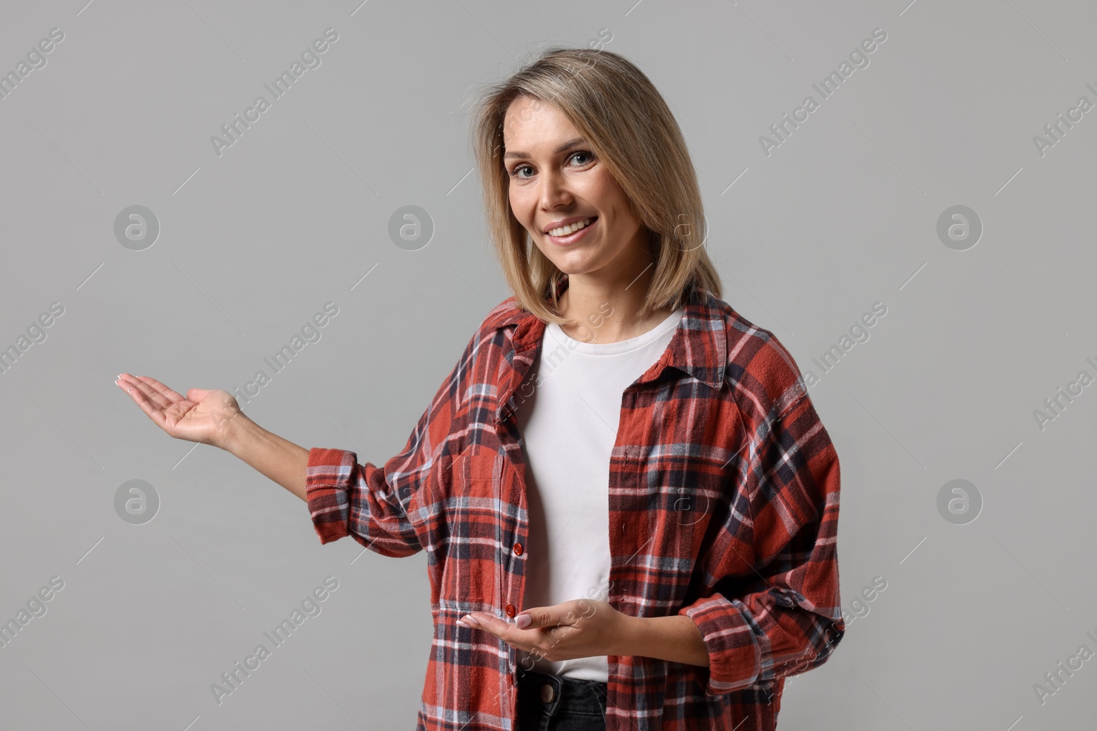 Photo of Woman welcoming friends or guests on grey background