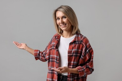 Photo of Woman welcoming friends or guests on grey background