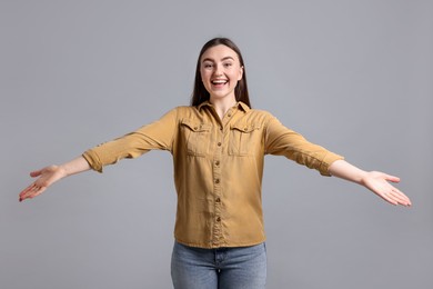 Photo of Woman welcoming friends or guests on grey background