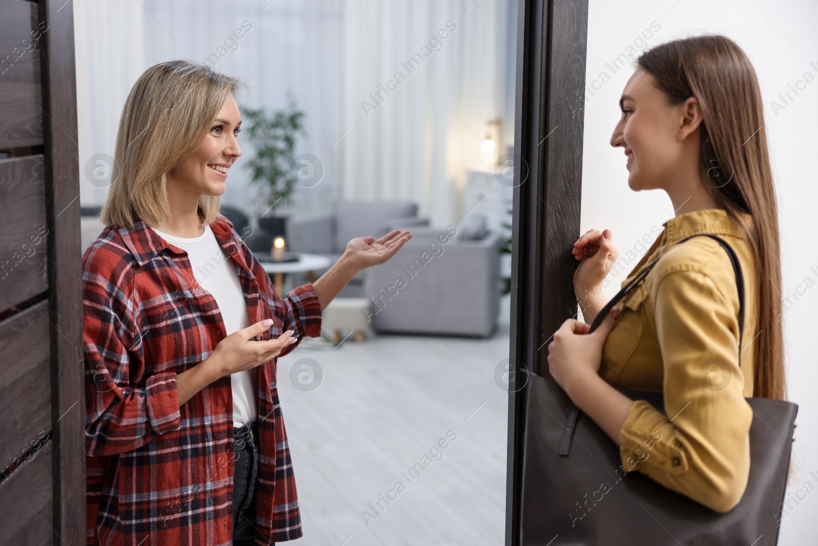 Photo of Cheerful woman welcoming guest to her apartment