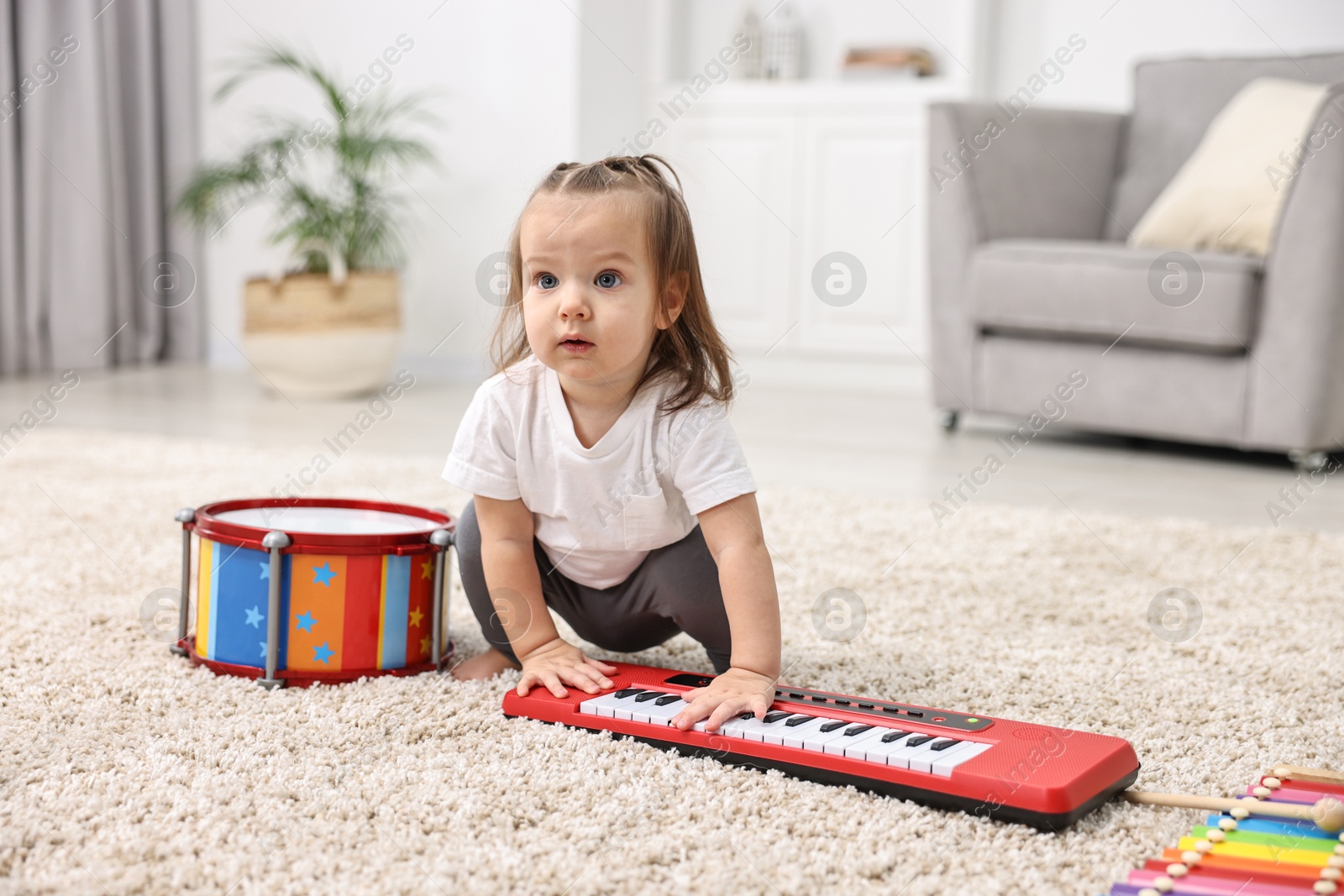 Photo of Cute little girl playing with toy piano at home