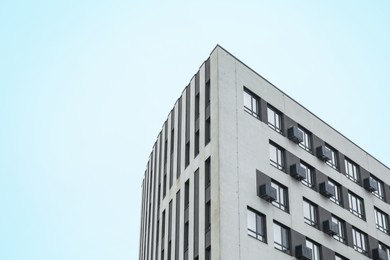 Photo of Modern building with many windows against blue sky, low angle view. Space for text