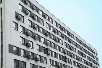 Modern building with many windows against blue sky, low angle view