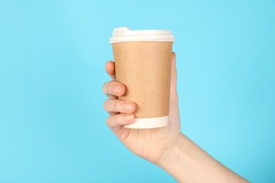 Photo of Woman holding paper cup on light blue background, closeup. Mockup for design