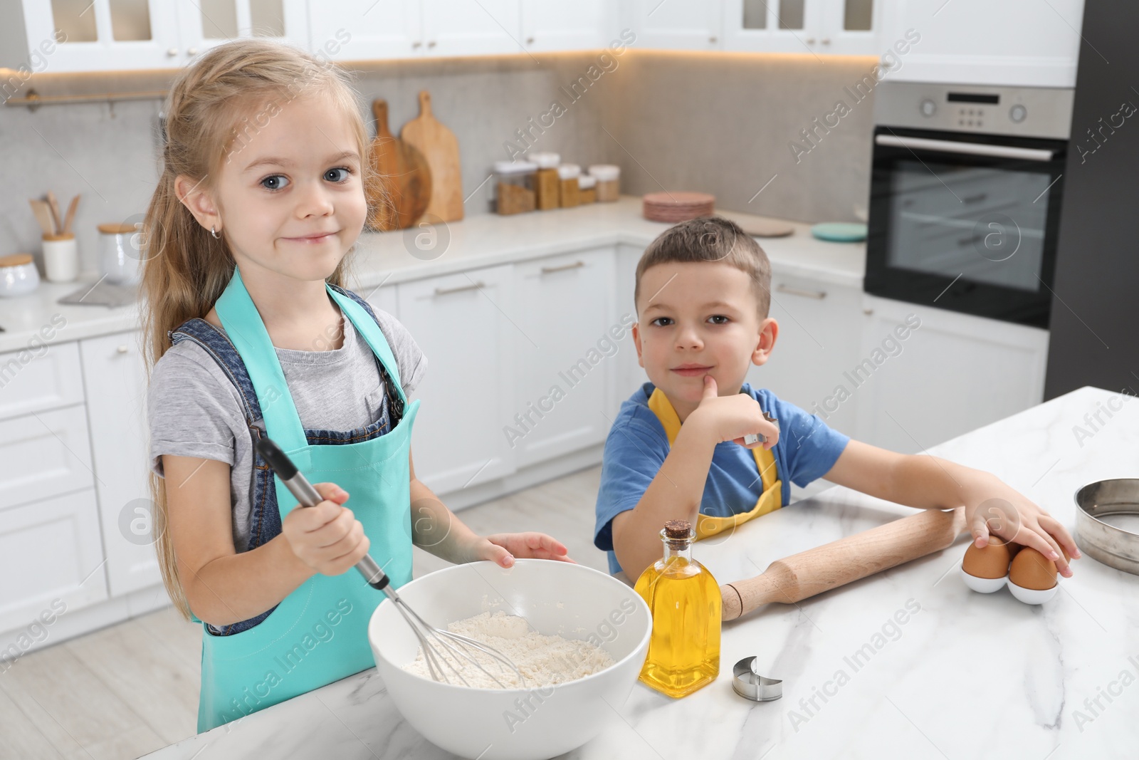 Photo of Little helpers. Children making dough for cookies in kitchen at home