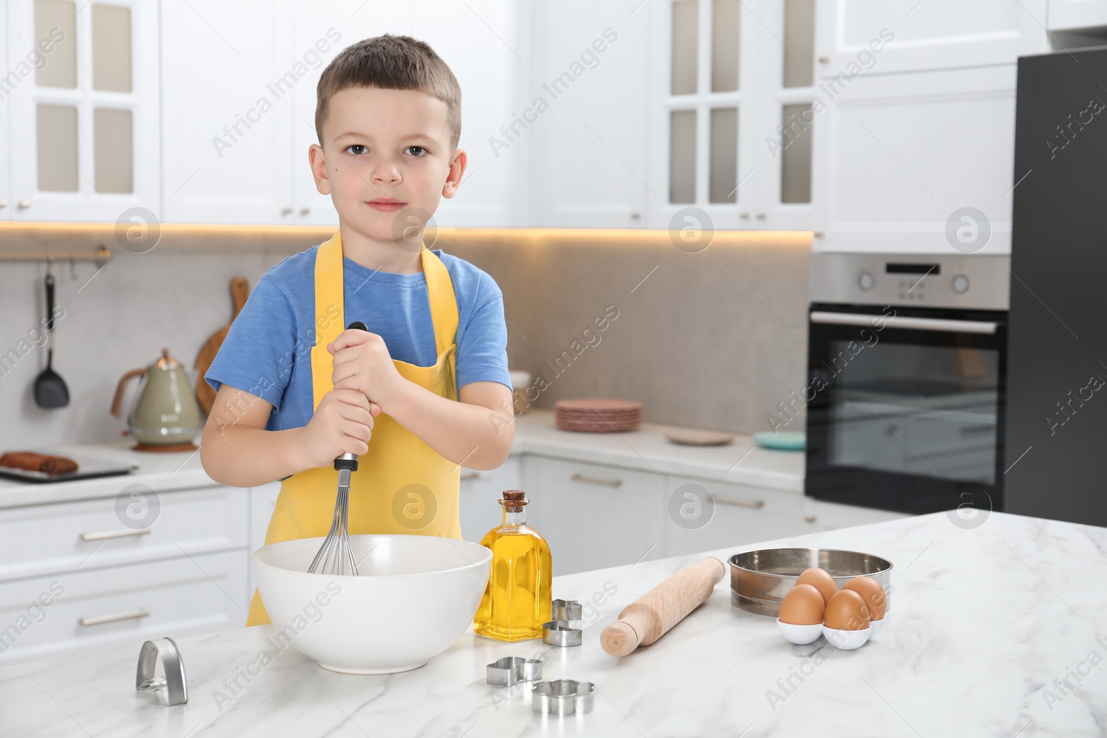 Photo of Little helper. Cute boy making dough for cookies in kitchen at home, space for text