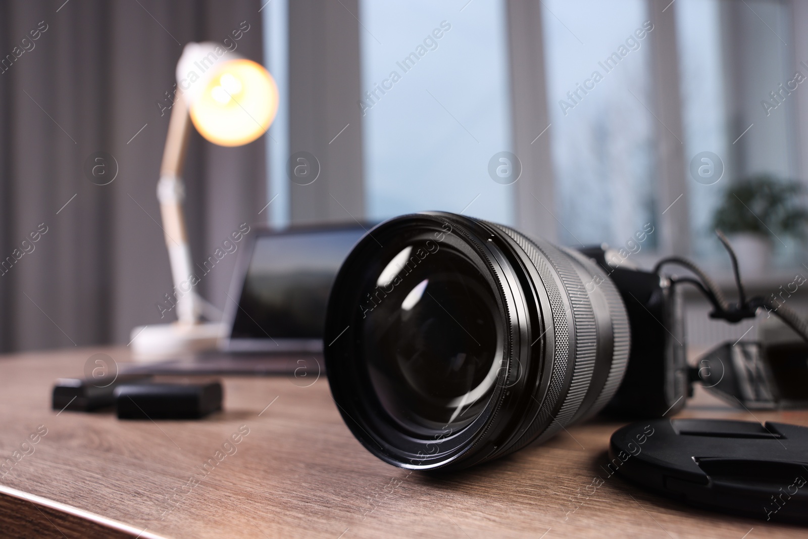 Photo of Professional photo camera and laptop on wooden desk indoors, selective focus. Space for text