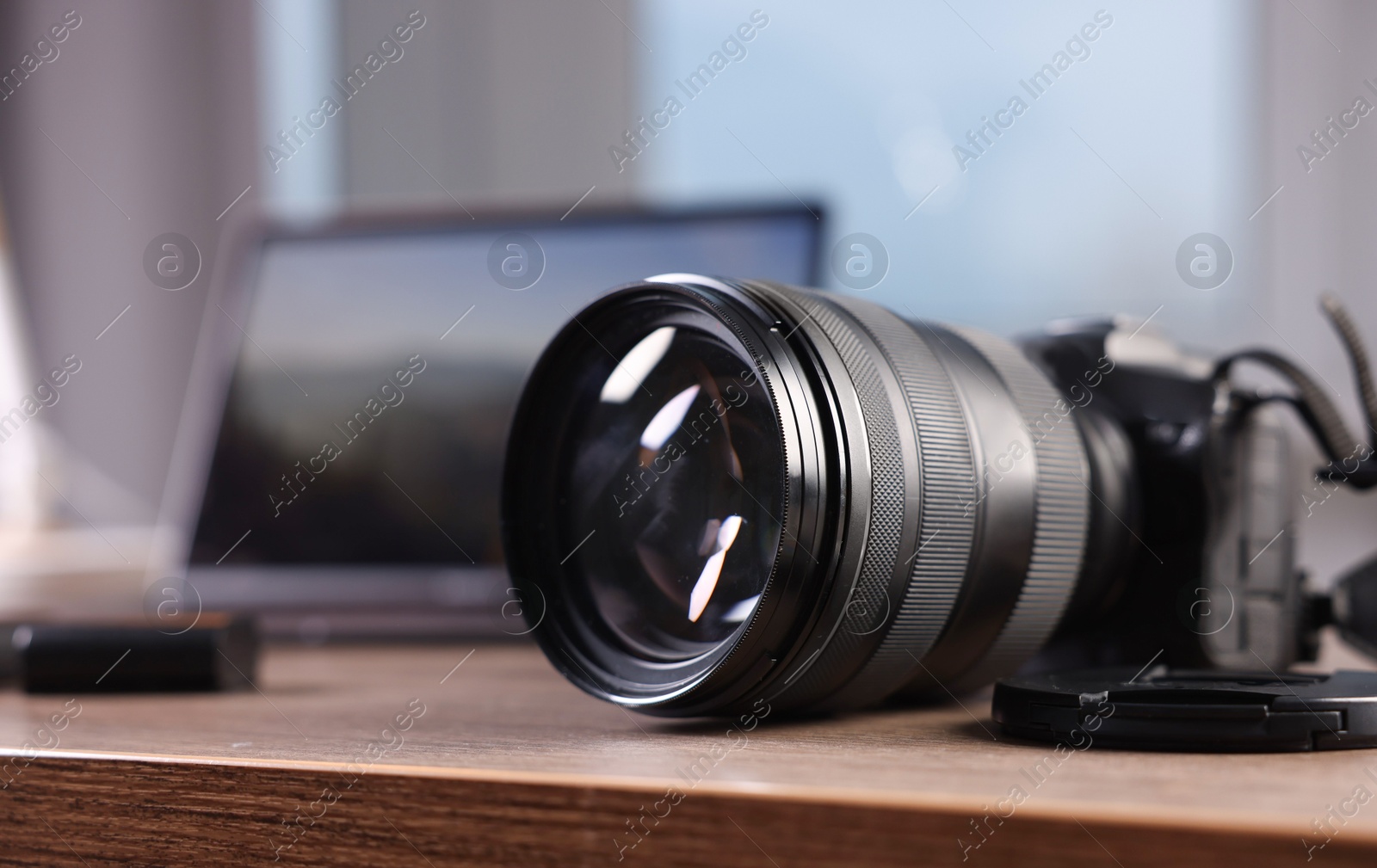 Photo of Professional photo camera and laptop on wooden desk indoors, selective focus