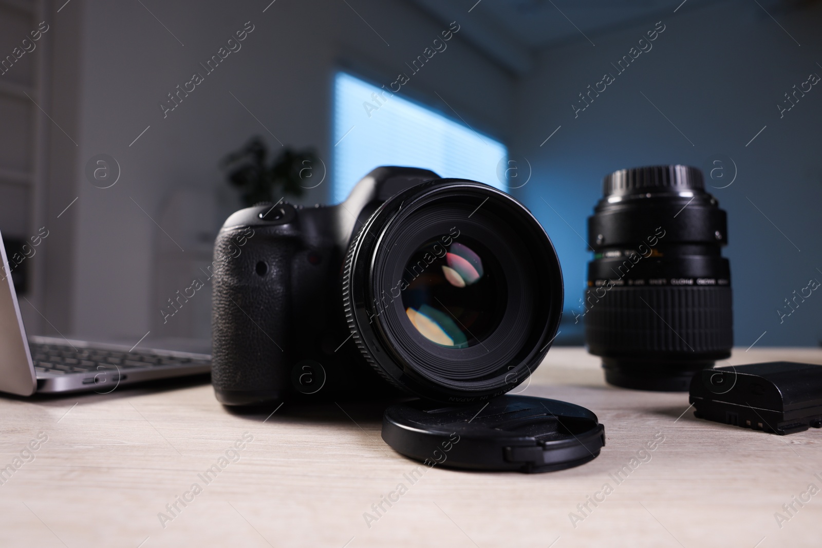 Photo of Professional photo camera, lens and laptop on wooden desk indoors, selective focus