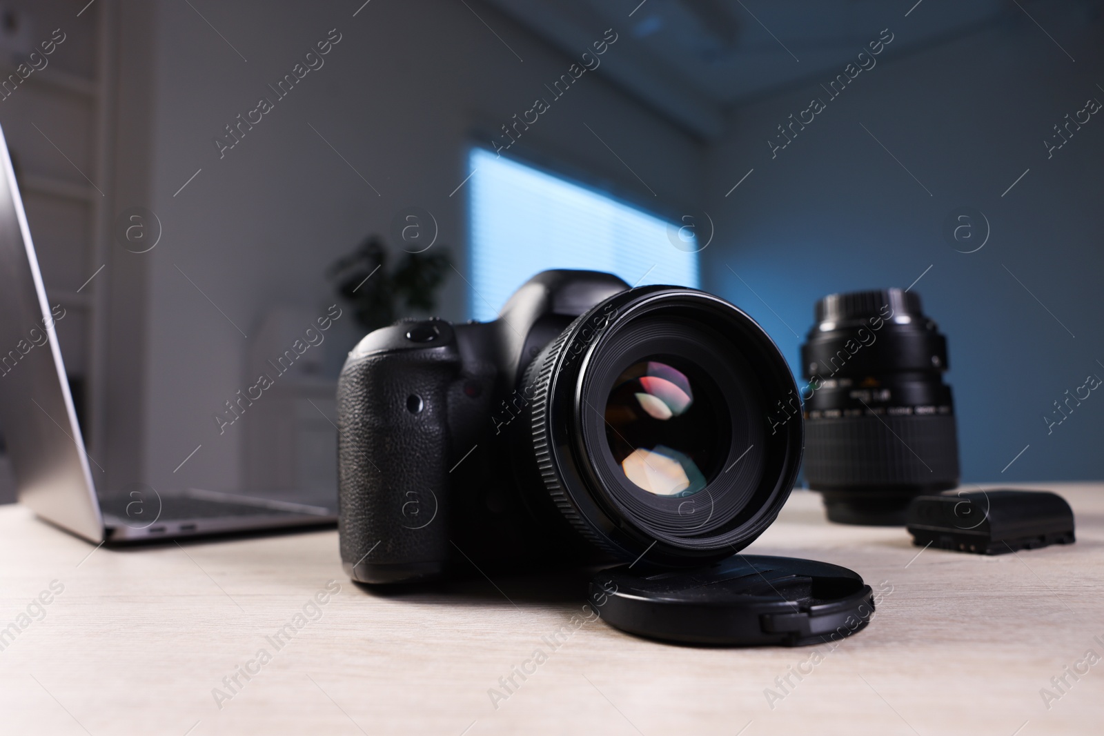 Photo of Professional photo camera, lens and laptop on wooden desk indoors, selective focus