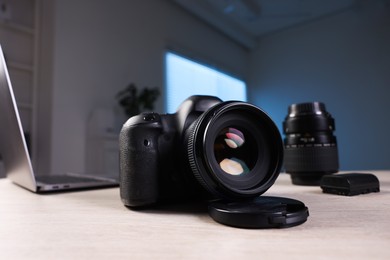 Photo of Professional photo camera, lens and laptop on wooden desk indoors, selective focus