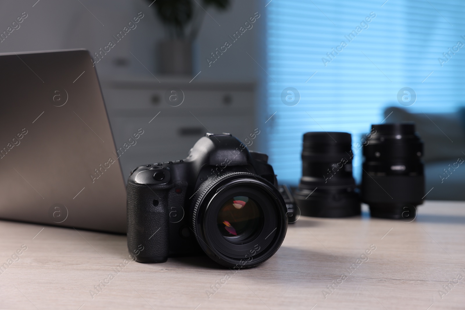 Photo of Professional photo camera, lenses and laptop on wooden desk indoors, selective focus. Space for text