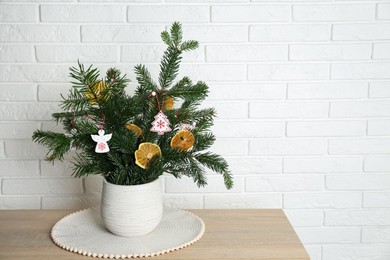 Photo of Beautiful Christmas composition of decorated fir tree branches on wooden table near white brick wall, space for text