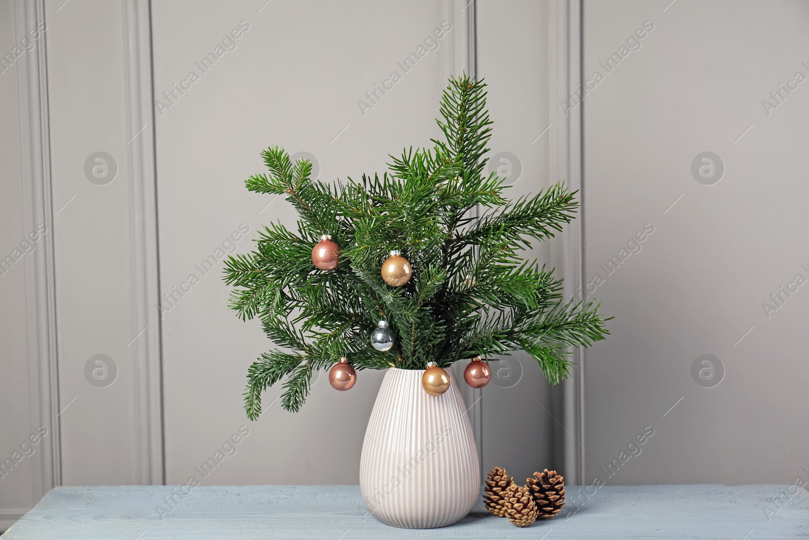 Photo of Decorated fir tree branches and cones on gray wooden table indoors. Christmas decor