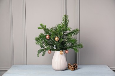 Photo of Decorated fir tree branches and cones on gray wooden table indoors. Christmas decor