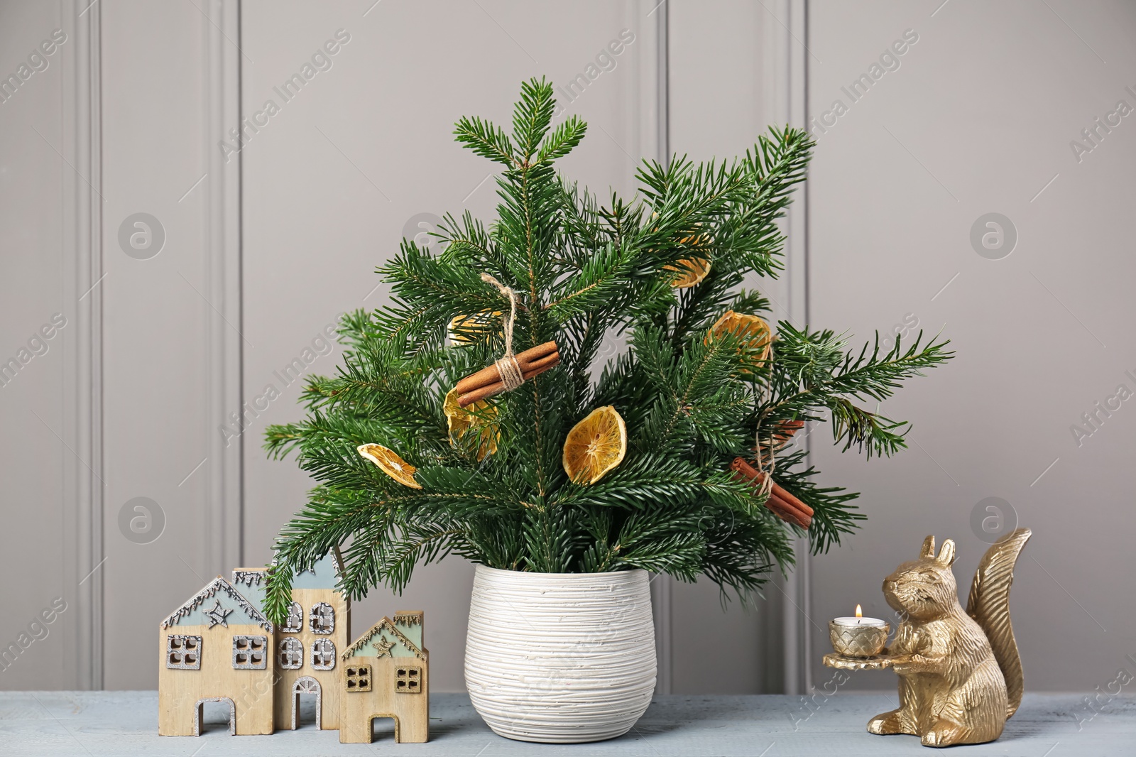 Photo of Beautiful Christmas composition of decorated fir tree branches on gray wooden table near indoors