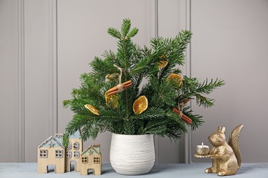 Photo of Beautiful Christmas composition of decorated fir tree branches on gray wooden table near indoors