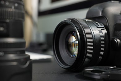 Photo of Professional camera and lens on black desk, selective focus